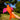 Orange bird-shaped toy with pink wings held in a hand against a blurred outdoor background