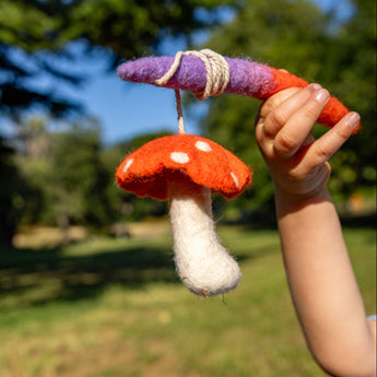 Hand holding a toy mushroom against a blurred outdoor background