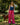 Woman in blue top and pink striped pants standing with a dog on a leash in a park.